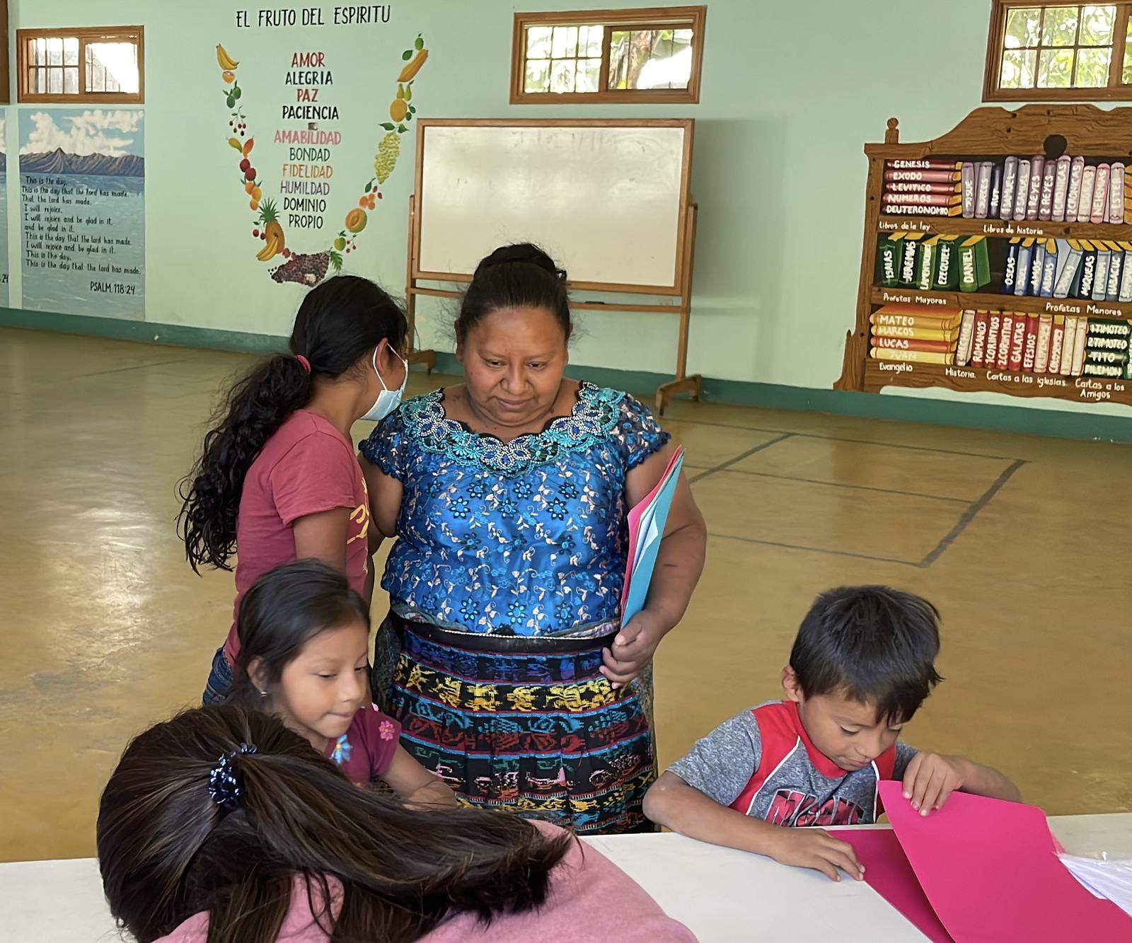 Lady looking over children crafts aleluya